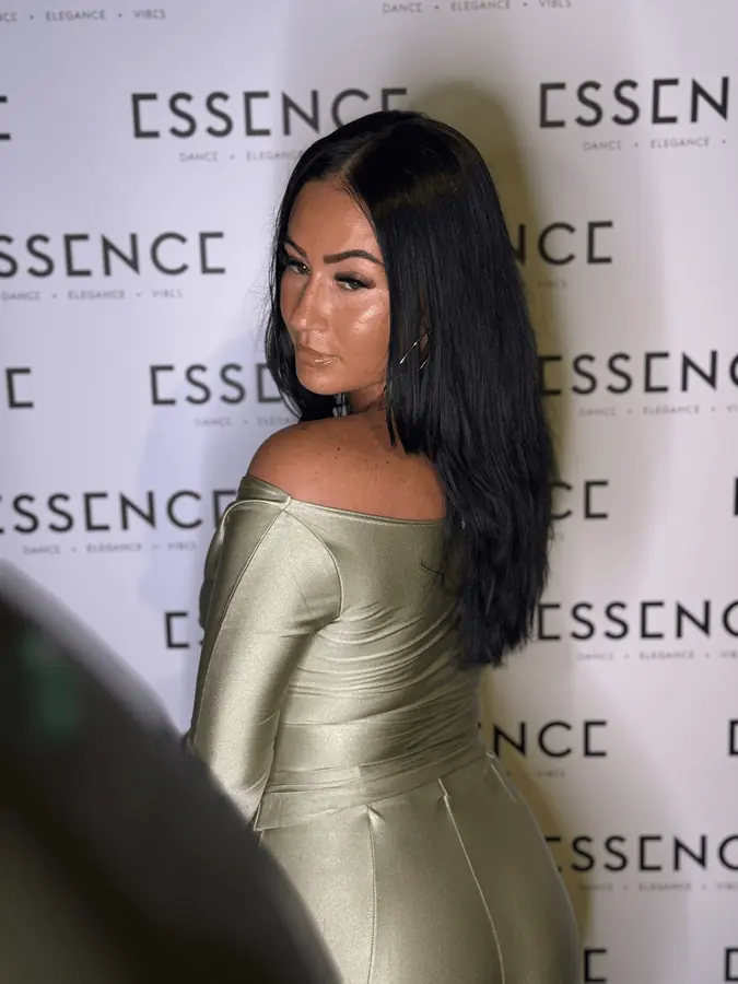A guest posing at the Essence backdrop