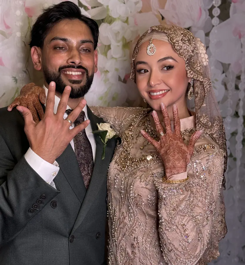 A bride and groom showing their henna and rings